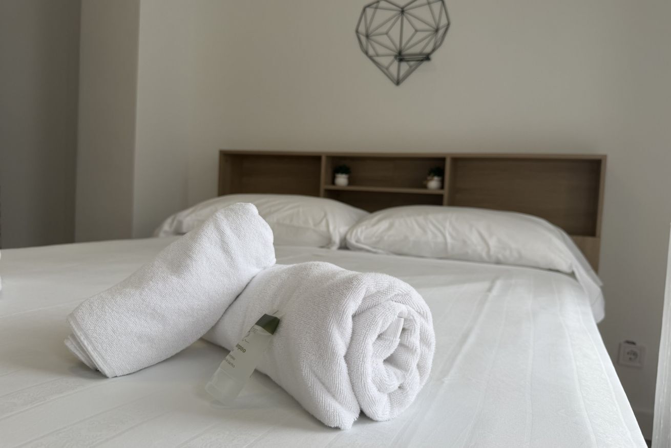 A neatly made bed with white linens and a geometric wall decoration.