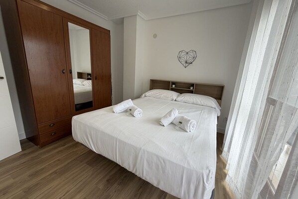 A bedroom with a bed, wooden wardrobe, and a heart-shaped wall decoration.