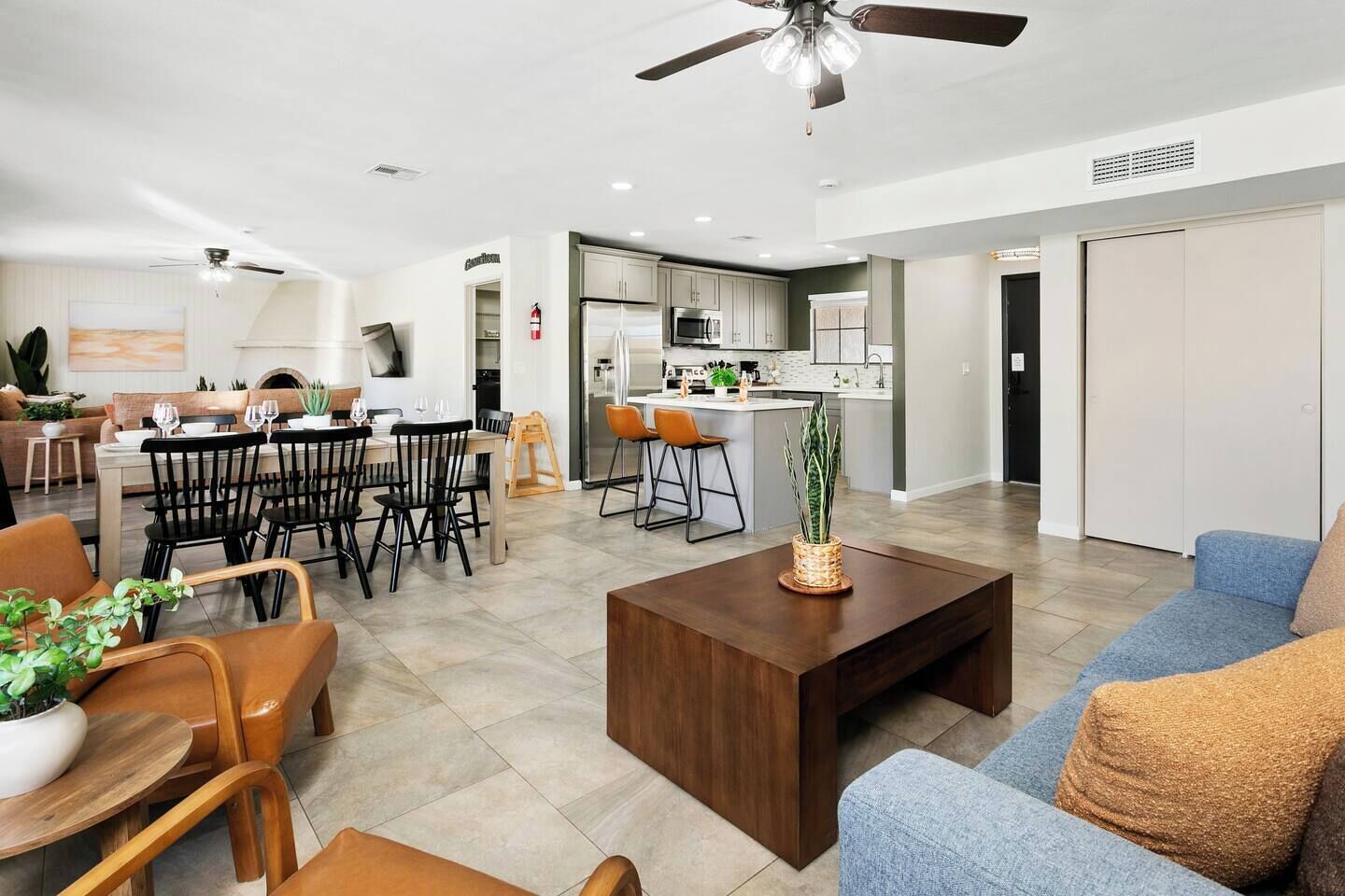 A modern living room with a dining area, kitchen, and a large window.