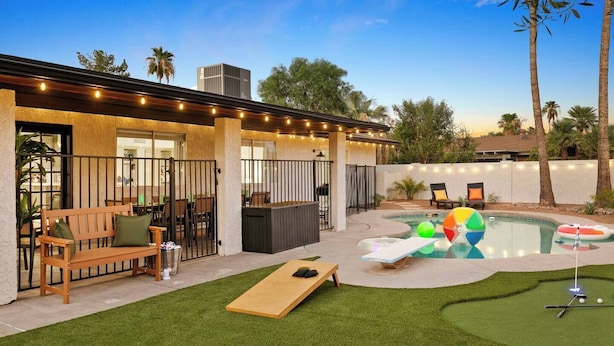Un patio trasero con piscina, jacuzzi, terraza de madera y zona de patio.