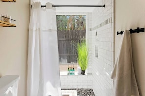A bathroom with a shower curtain, a potted plant, and a towel rack.