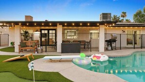 Un patio trasero con piscina, un pequeño césped y una zona de terraza.