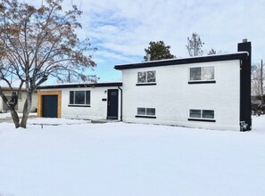 A two-story residential building with a snow-covered ground, a garage door, and a front door. - Cozy West Elm Stay Near Expo & Mountain Fun (Sandy)
