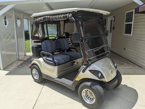 A golf cart parked in a covered area with a mesh canopy, a seat, and a steering wheel. - 
This beautiful stick-built home has just been remodeled. In Spanish Springs (Lady Lake)