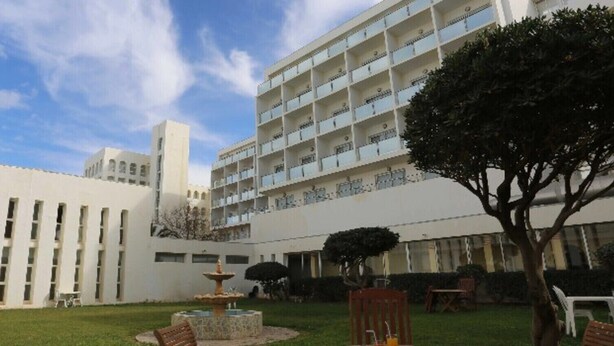 A courtyard with a fountain, a tree, and a building with multiple balconies. - Hotel Mazafran (Algiers)