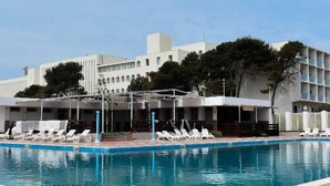 A hotel with a swimming pool, lounge chairs, and a covered area. - Hotel Mazafran (Algiers)
