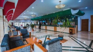 A hotel lobby with seating areas, a reception desk, and a staircase. - Hotel Mazafran (Algiers)