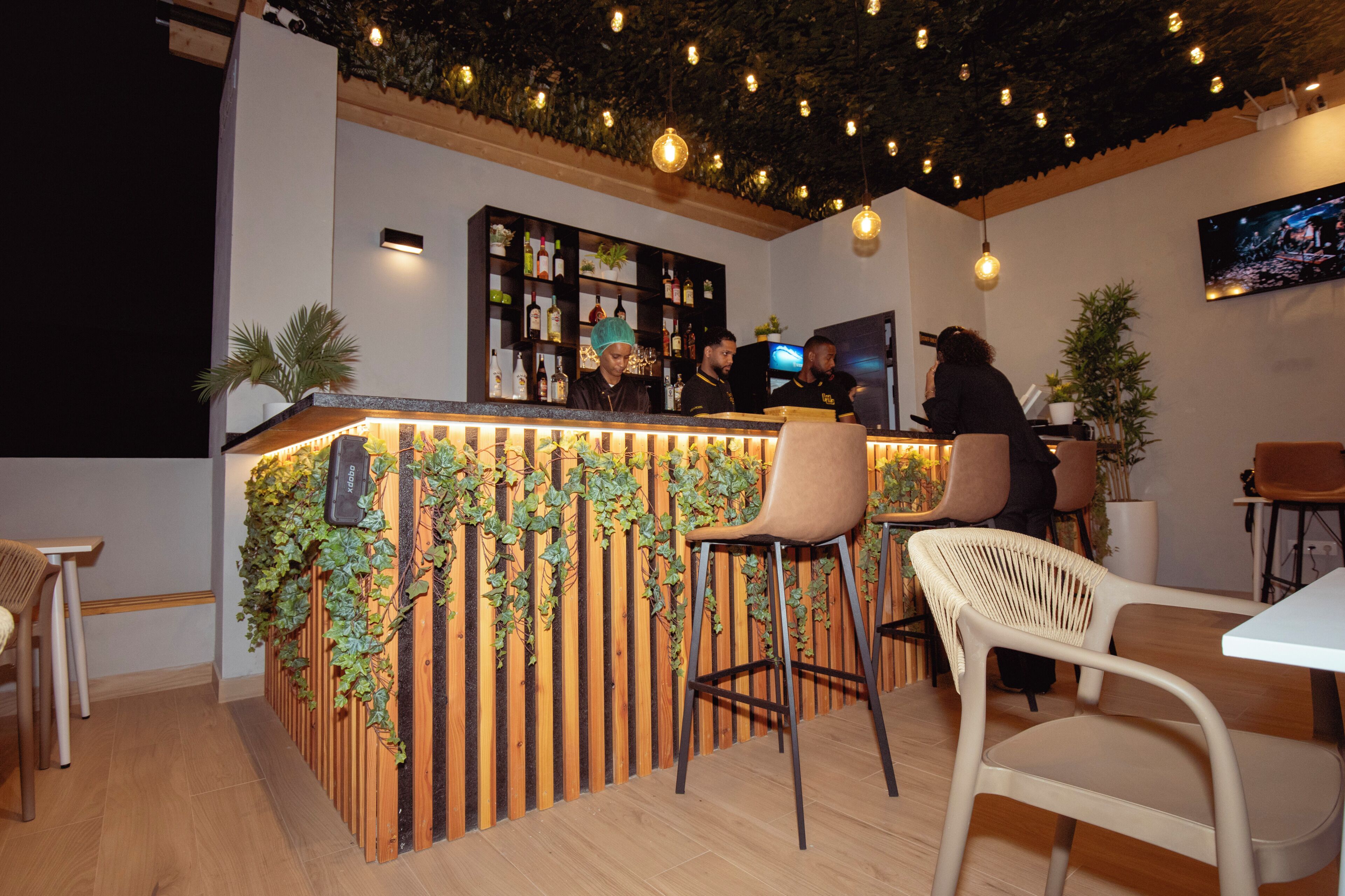 A bar area with wooden paneling, bar stools, and a television screen.