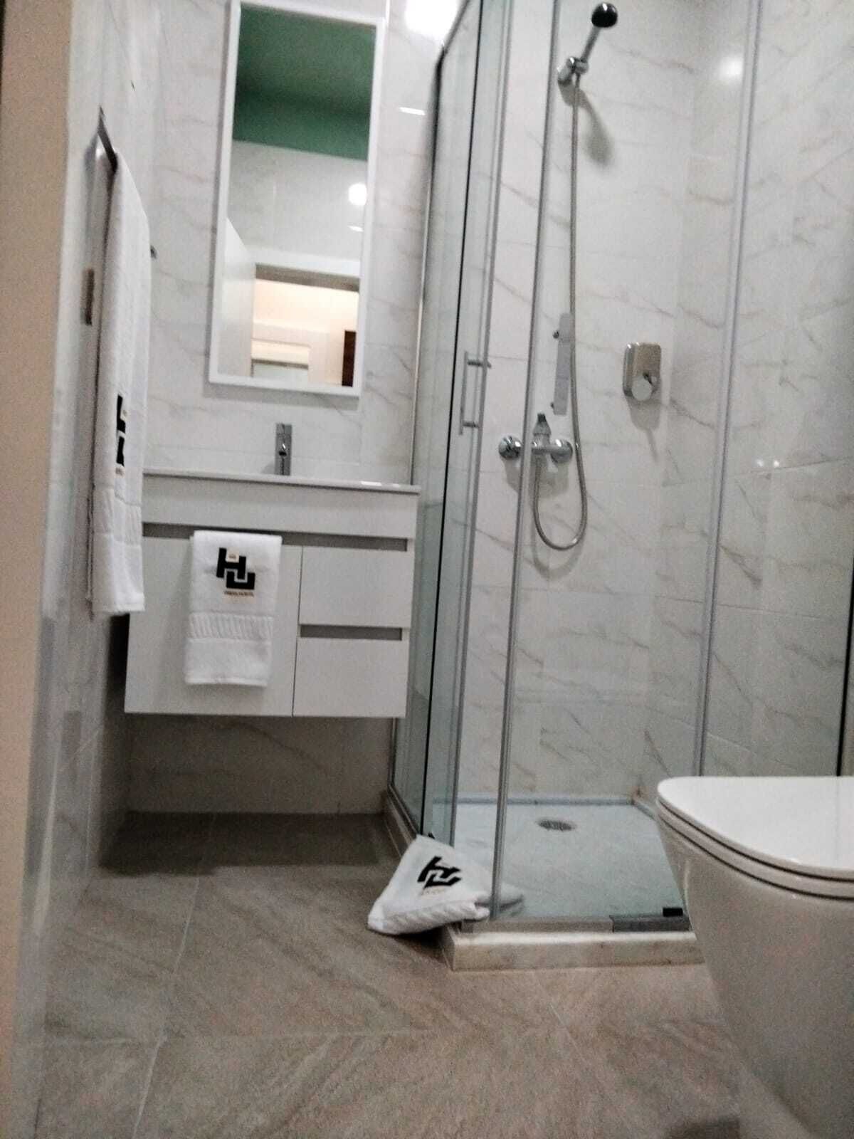 Une salle de bain moderne avec une douche à parois de verre, des toilettes et un meuble-lavabo avec un miroir.