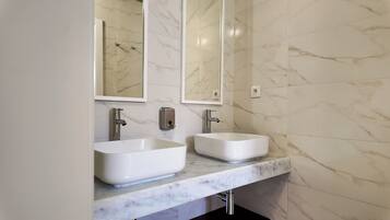 A bathroom with two sinks, a mirror, and a marble wall.