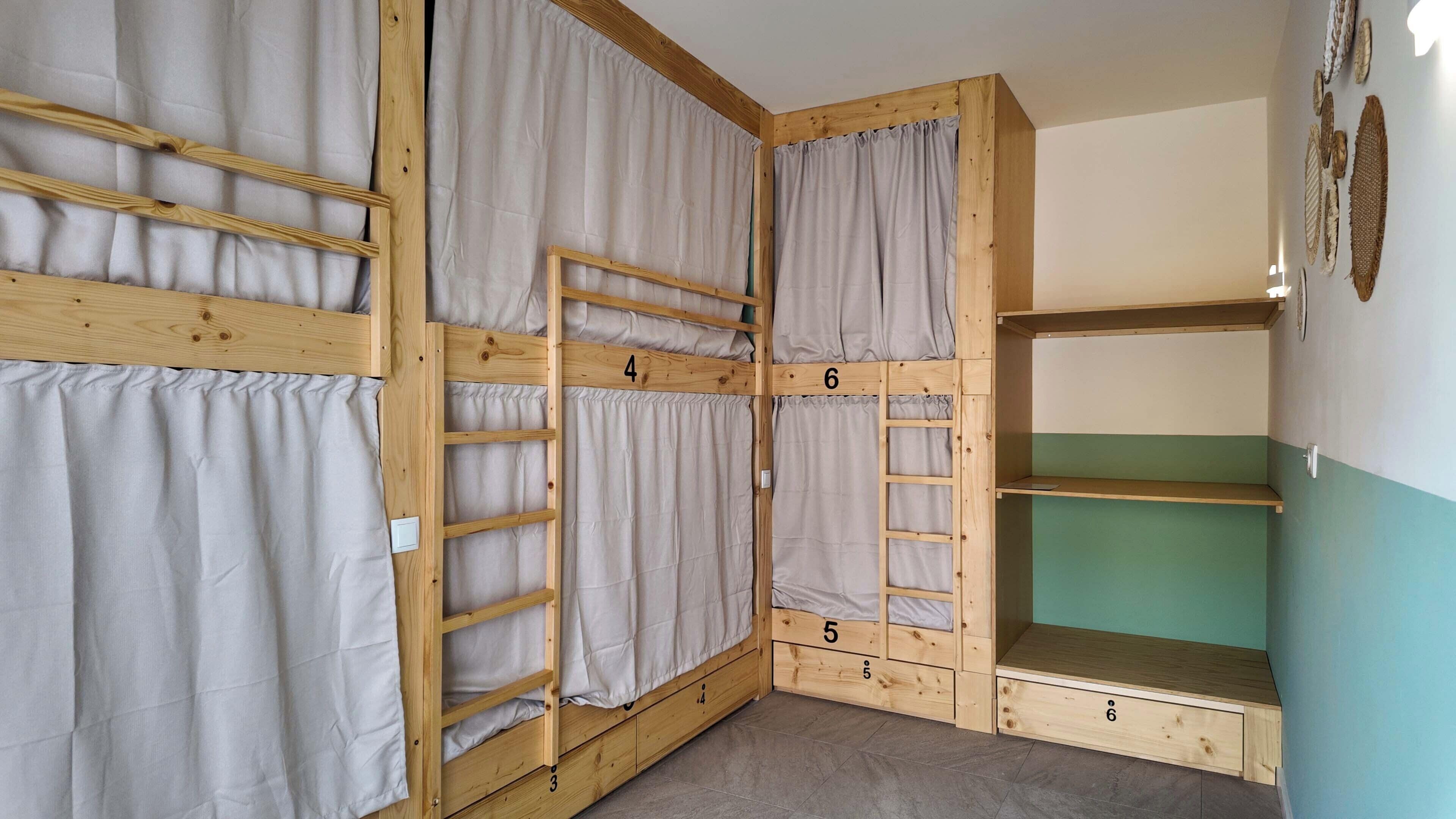 Une chambre avec des lits superposés, une échelle, des lits numérotés et un petit bureau.