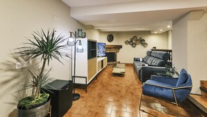 A living room with a sofa, a coffee table, a TV, and a plant.
