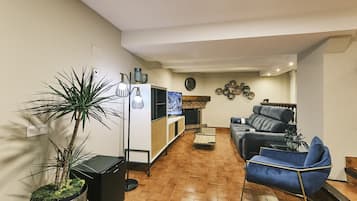 Una sala de estar con un sofá, una mesa de centro, un televisor y una planta.