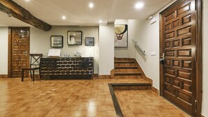 A reception area with a wooden reception desk, a staircase, and a large wooden door.