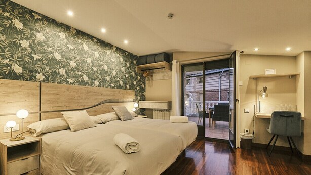 A hotel room with a large bed, a desk, and a view of the city.