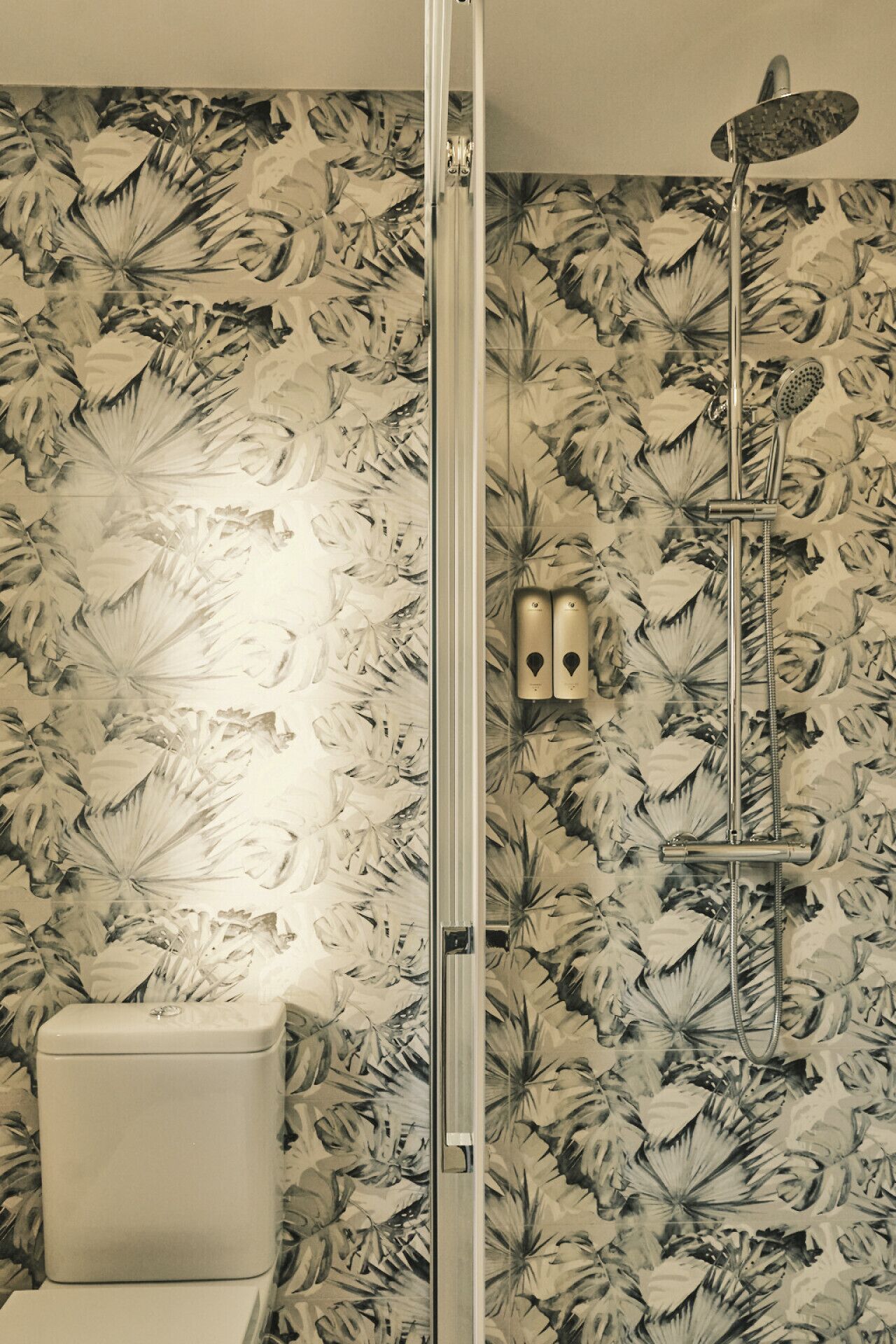 Een badkamer met een douche, toilet en een bloemenprint op de muur.