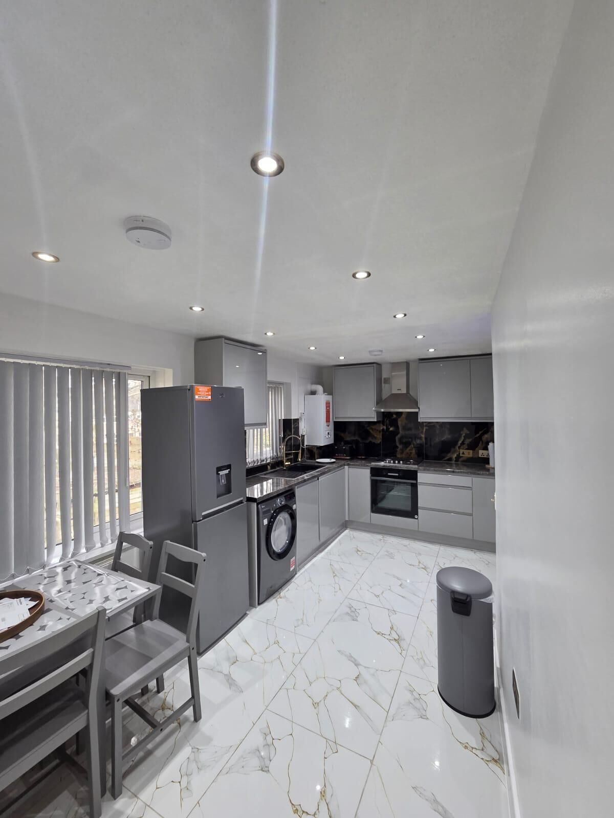 A modern kitchen with a central island, built-in appliances, and a dining area with a table and chairs.