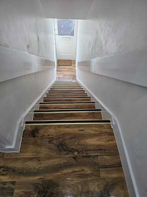 Una escalera de madera con escalones que conducen a un rellano con ventanal.