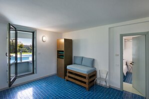 Ein Zimmer mit einem Bett, einem Holzschrank, einem Stuhl und Blick auf einen Swimmingpool.