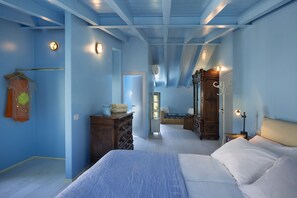 Ein Schlafzimmer mit einem großen Bett, einem Schminktisch und einem Spiegel. Eine Tür führt in einen weiteren Raum.