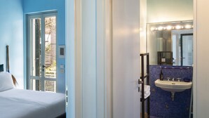 Ein Hotelzimmer mit einem Bett, einem Badezimmer mit Waschbecken und Spiegel sowie Blick nach draußen.