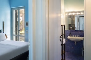 Ein Hotelzimmer mit einem Bett, einem Badezimmer mit Waschbecken und Spiegel sowie Blick nach draußen.