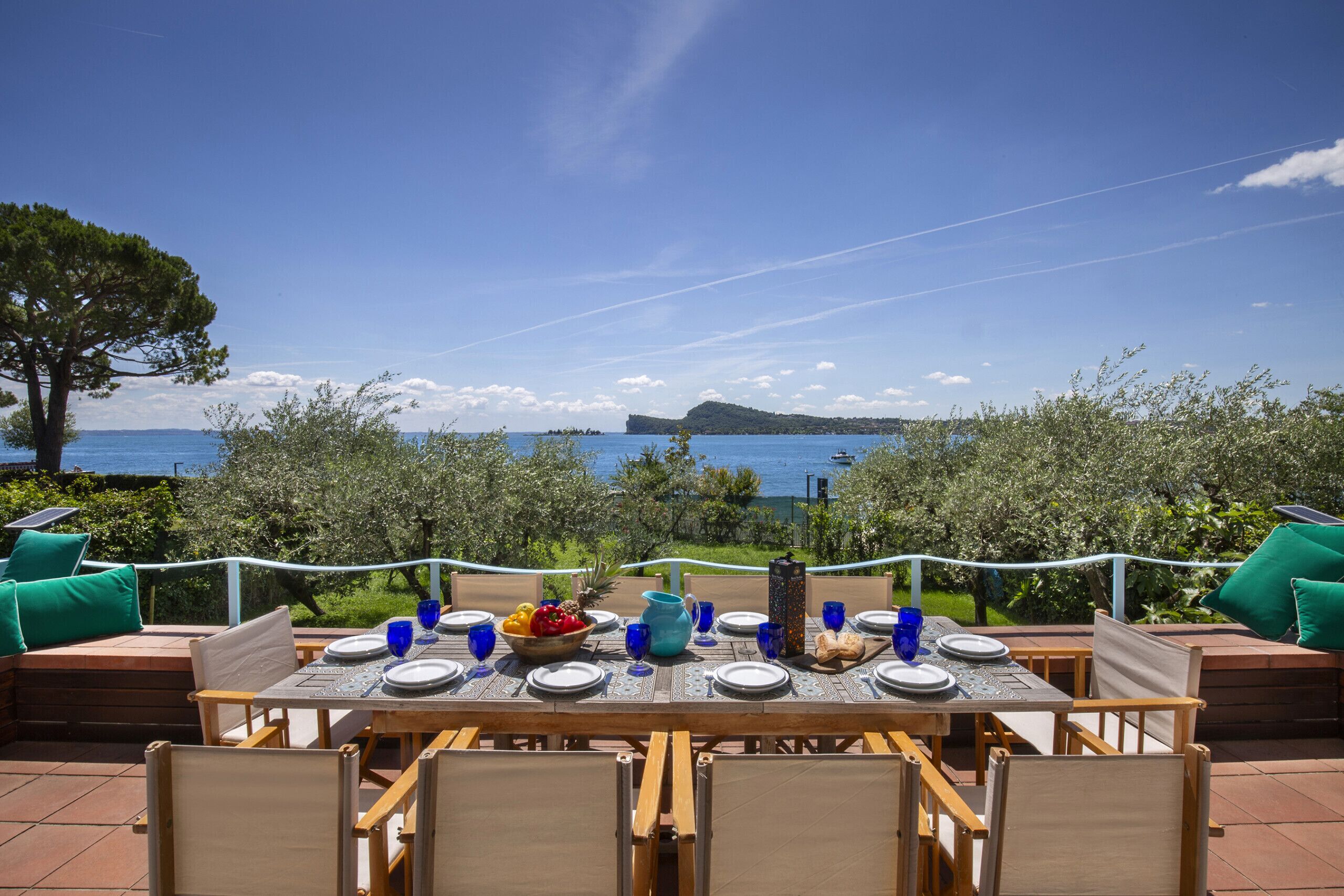 An outdoor dining area with a view of the sea and a distant island.