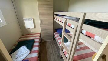 Une petite pièce compacte avec des lits superposés, une fenêtre et un climatiseur fixé au mur.