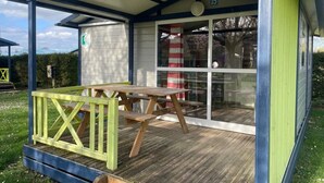 A covered outdoor area with a picnic table and a glass door entrance. - Chalet 3 étoiles - Piscine  - ccbgahh (Chatel-Chéhéry)