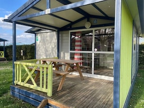 Een overdekt buitengebied met een picknicktafel en een glazen deur.