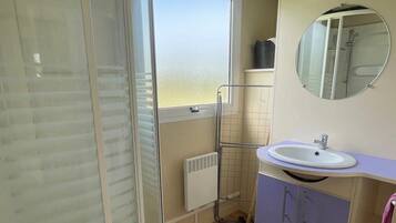 Une salle de bain avec une douche, un lavabo et un miroir.