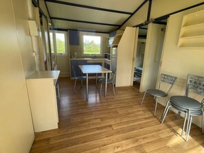 A compact kitchen with a dining table and chairs, a small window, and a kitchenette area. - Chalet 3 étoiles - Piscine  - ccbgahi (Chatel-Chéhéry)