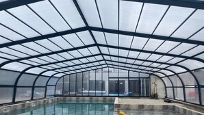 A large indoor swimming pool with a glass ceiling and a yellow sculpture in the center. - Chalet 3 étoiles - Piscine  - ccbgahi (Chatel-Chéhéry)