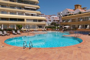 A swimming pool with sun loungers and umbrellas, surrounded by multi-story buildings with balconies. - Santa Maria 151 - Studio (Costa Adeje)