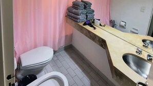 Ein Badezimmer mit Toilette, Waschbecken und einem Handtuchhalter mit gefalteten Handtüchern.