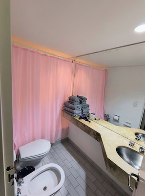 A bathroom with a toilet, sink, and a towel rack with folded towels. - Modern Apartment in Microcentro (Buenos Aires)