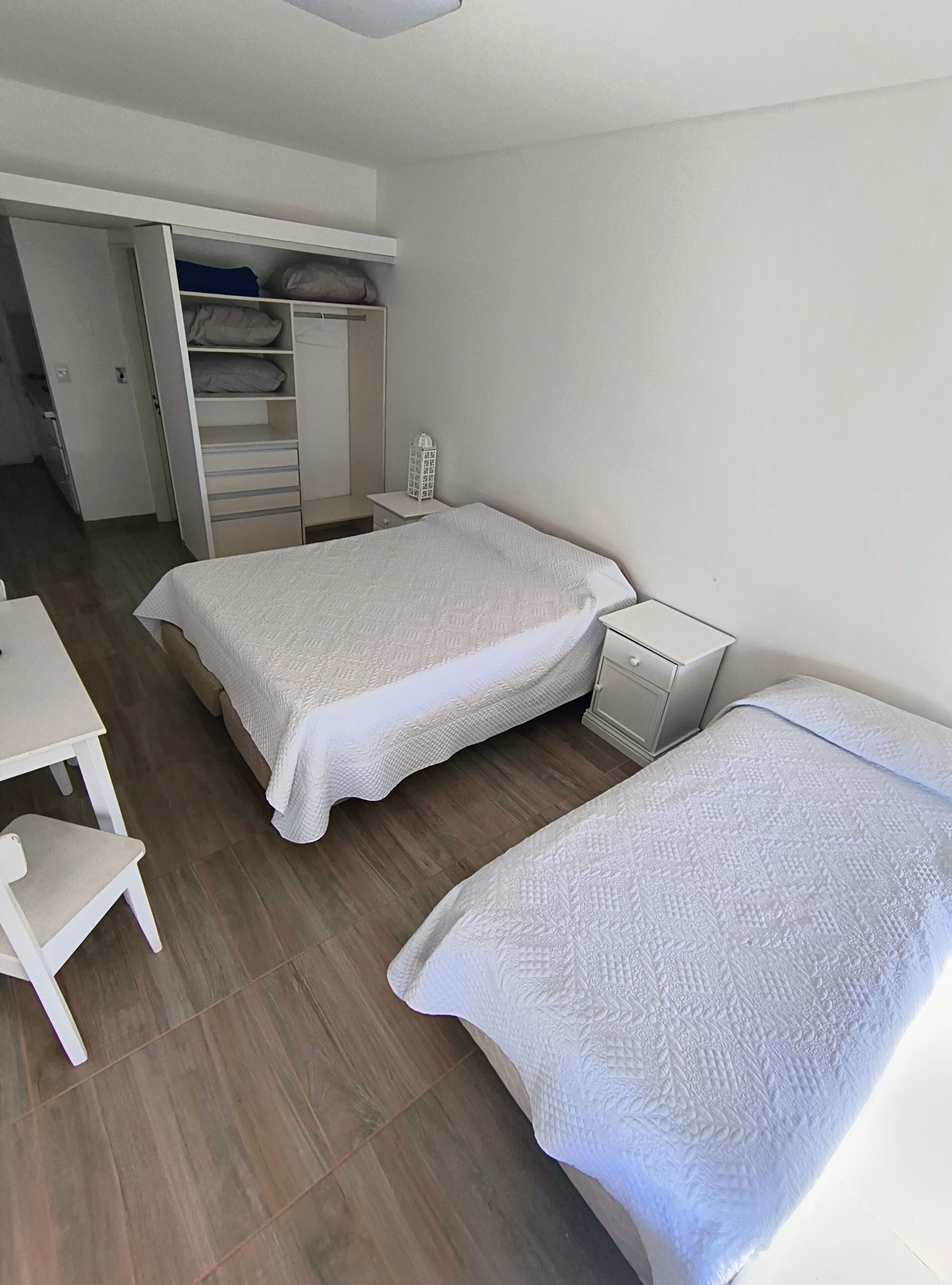 A bedroom with two beds, a desk, and a wardrobe.