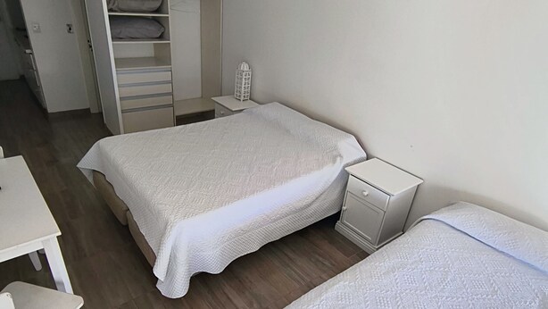 Ein Schlafzimmer mit zwei Betten, einem Schreibtisch und einem Kleiderschrank.