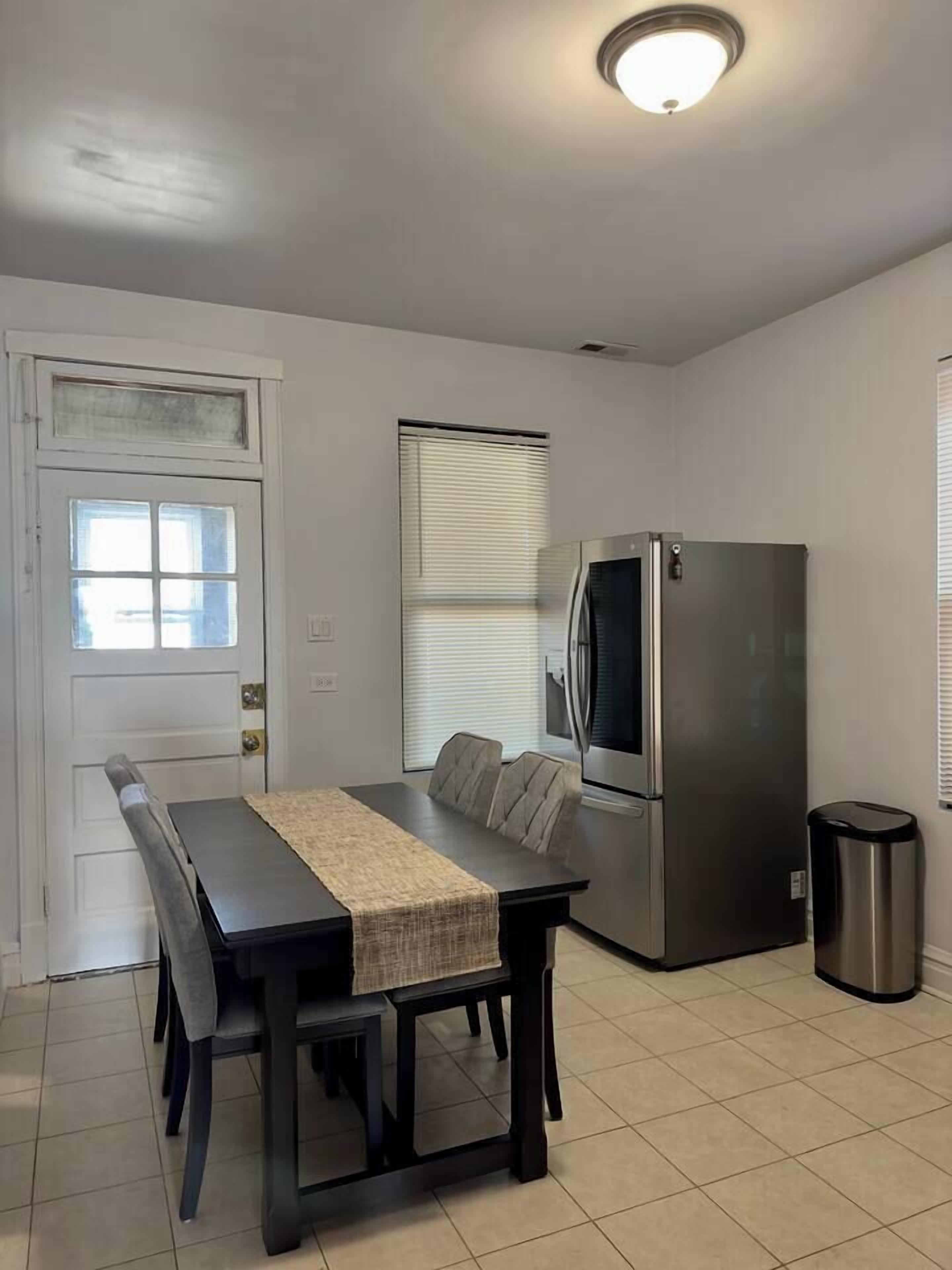 Une cuisine compacte comprenant une table à manger, un réfrigérateur et une poubelle.