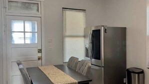 Uma cozinha compacta com mesa de jantar, geladeira e lixeira.