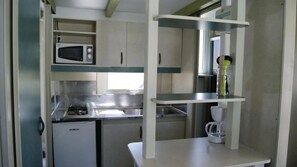 A compact kitchenette with a microwave, a small refrigerator, a sink, and a coffee maker.