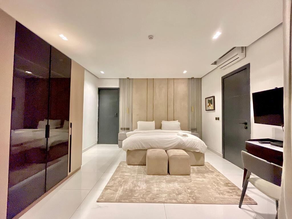 A modern bedroom with a large bed, bedside tables, a desk, and a television.