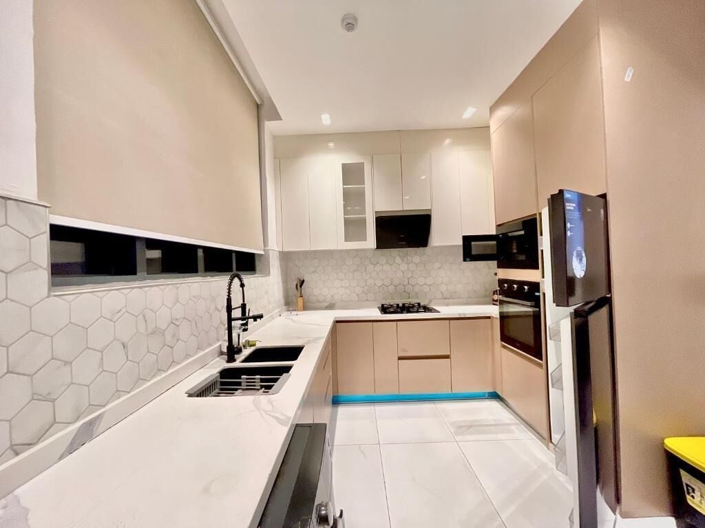 A modern kitchen with white countertops, a hexagonal tile backsplash, and built-in appliances including a stove, oven, and microwave.
