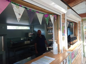 A kitchen area with a person standing behind a counter, a window, and various kitchen appliances.