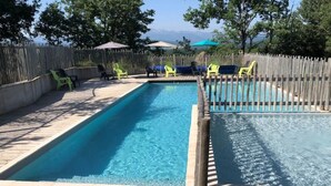 A rectangular pool with a wooden deck and a wooden fence.