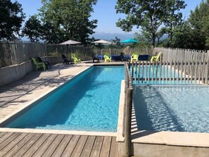A rectangular pool with a wooden deck and a wooden fence.