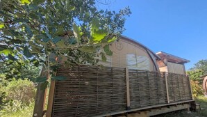 A covered outdoor area with a wooden structure, possibly a deck or patio, and a large tree overhead.