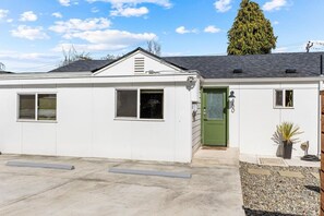 A single-story building with a green door, two windows, and a small porch area. - Burien Modern Cozy - Near Airport & Amenities (Burien)