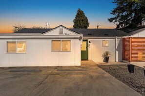 A single-story building with a green door, a small porch area, and a gravel pathway leading to the entrance. - Tranquil Burien Cozy - Near Airport & Amenities (Burien)