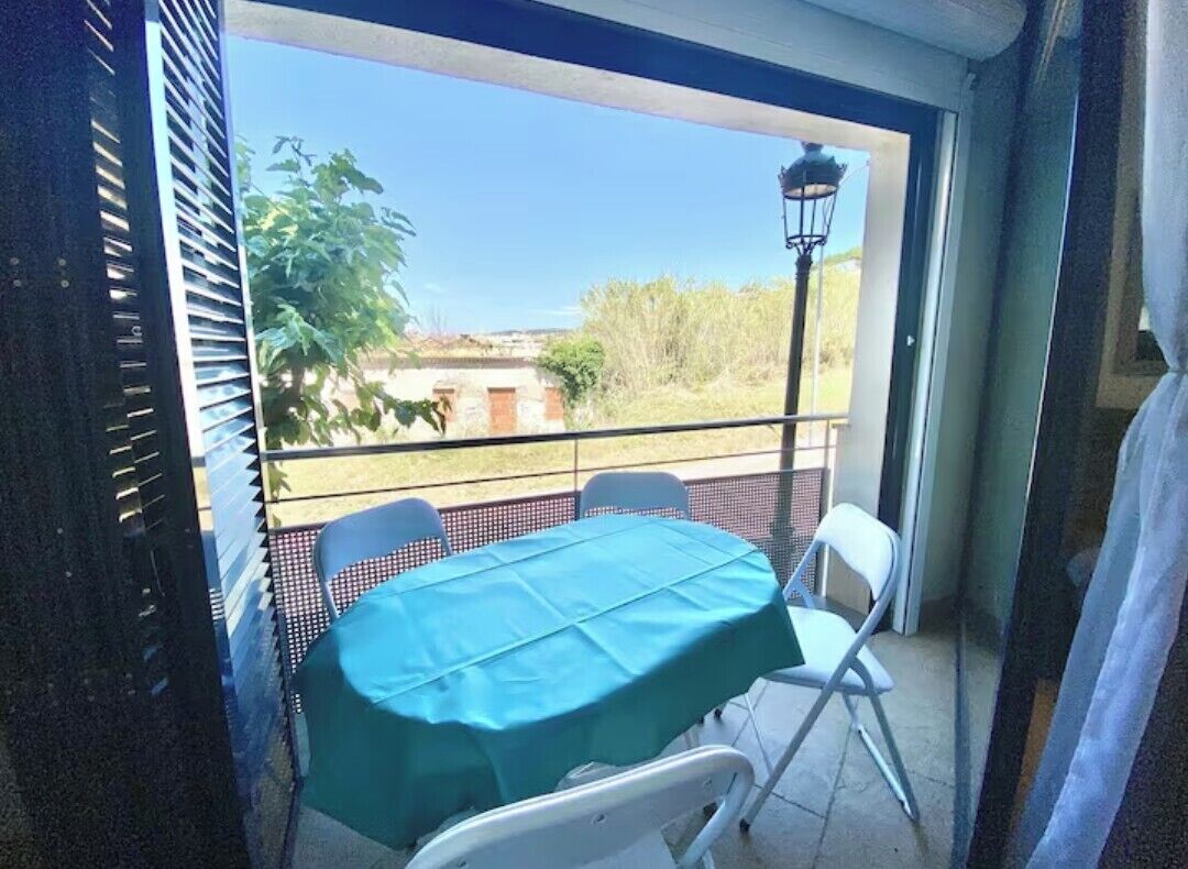 Un balcón con una mesa y sillas, vistas al exterior y un farol.